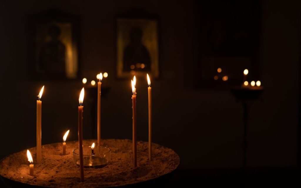 Candles illuminating orthodox icons in a dimly lit church setting, creating a warm atmosphere.