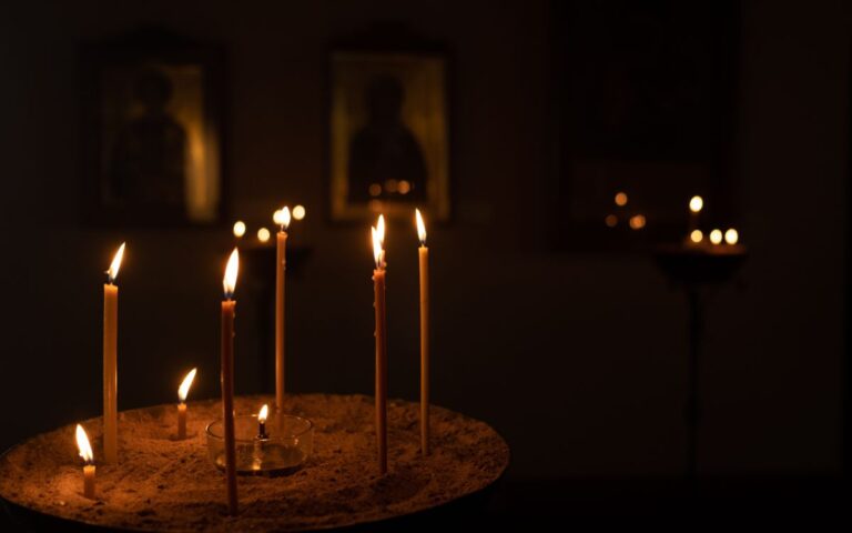 Candles illuminating orthodox icons in a dimly lit church setting, creating a warm atmosphere.