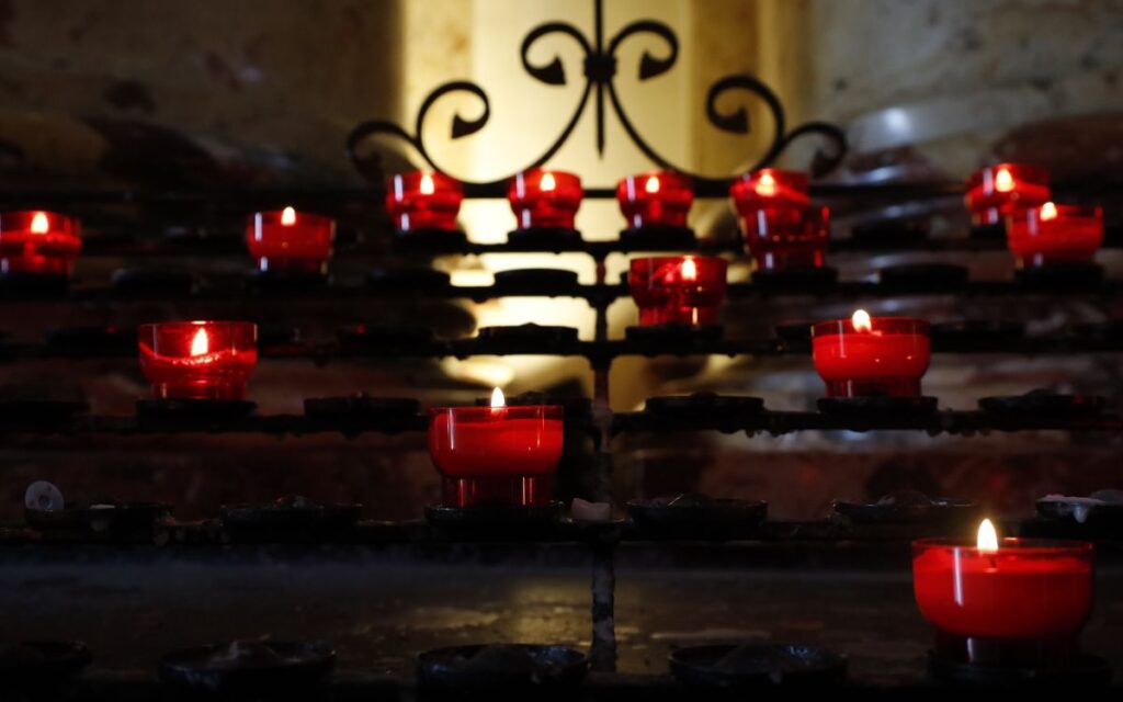 Red candles glowing in a church setting, providing a warm and serene atmosphere.