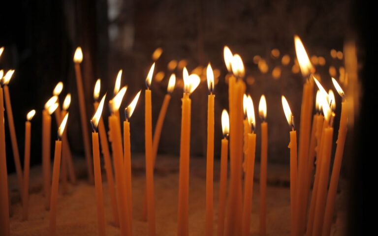 A serene scene of lit votive candles during a religious ceremony in a Larnaka church.