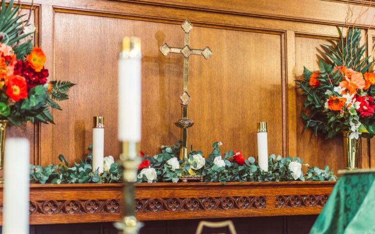 A beautifully decorated church altar featuring candles, flowers, and a wooden cross.