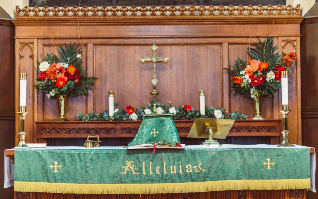 An ornate church altar with a crucifix, flowers, and religious symbols.