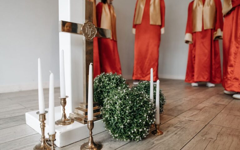 A church setting with choir members in red robes, candles, and a decorative cross.