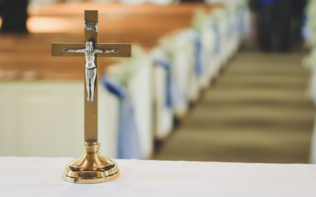 A gold crucifix on an altar with blurred church pews in the background.