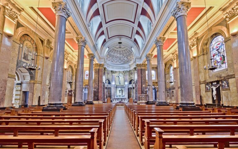 Bright view of a historic church interior in Preston, England, showcasing grand pillars and stained glass windows.