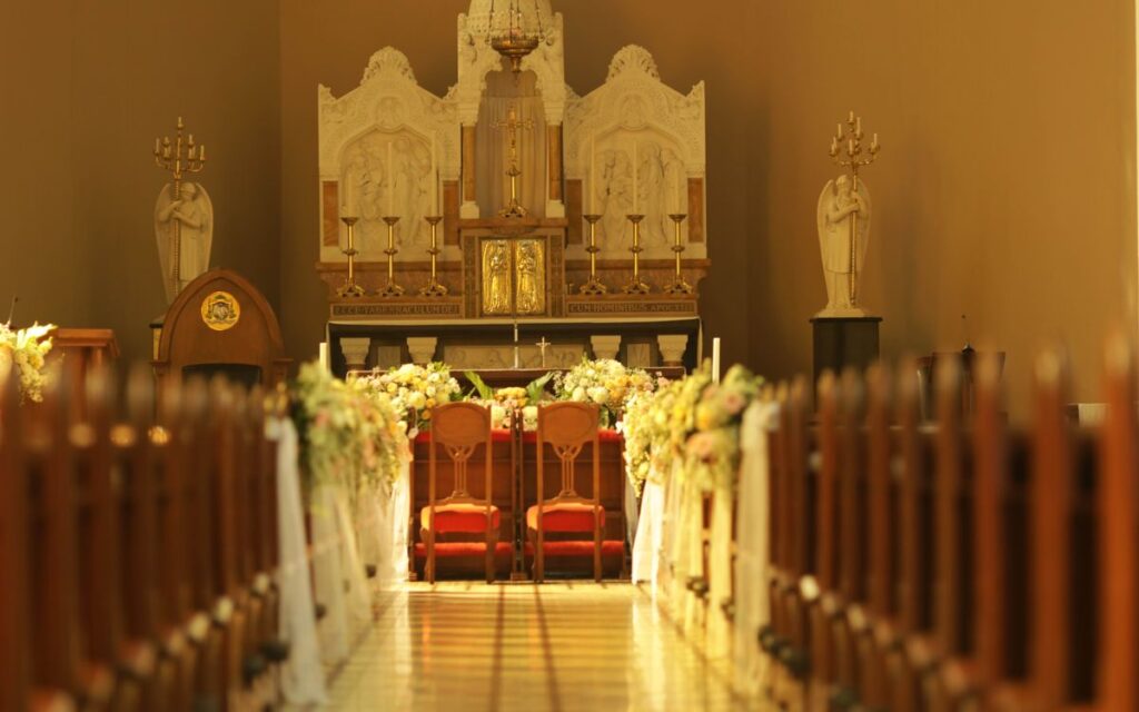 A beautifully decorated church interior with floral arrangements and ornate altar.