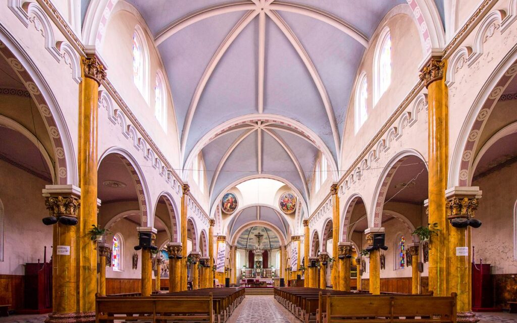 Elegant interior of a Catholic church with vaulted ceilings and ornate design, highlighting religious architecture.